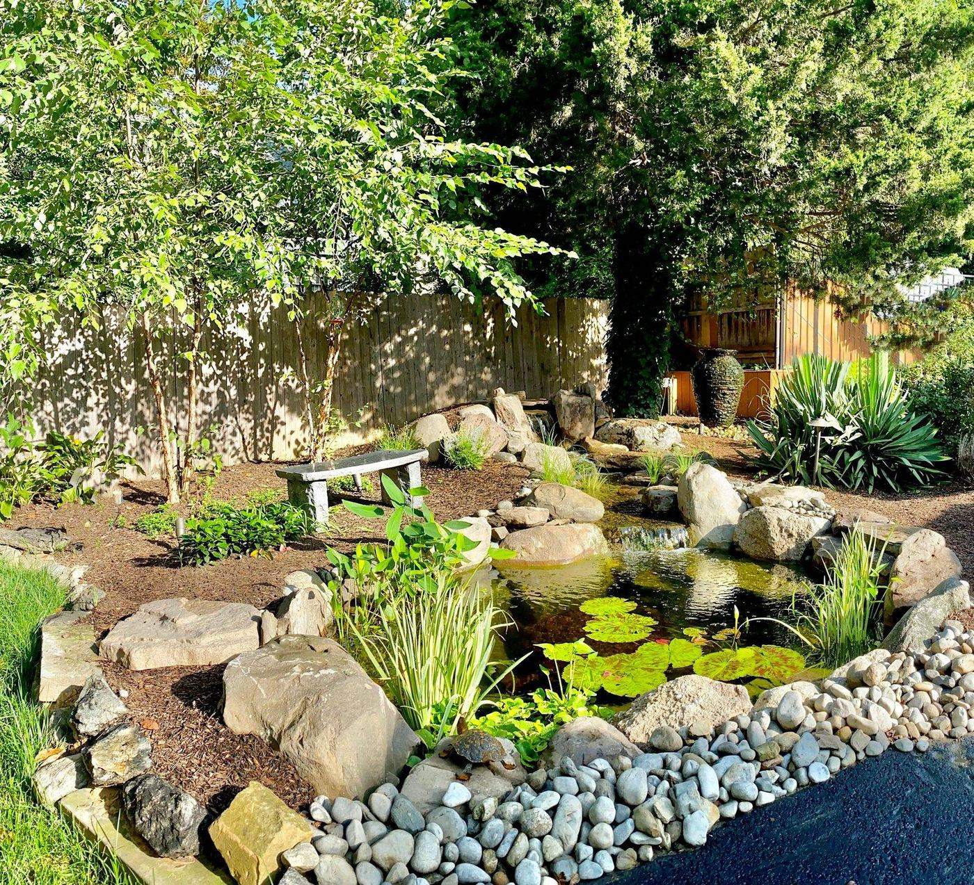 Garden pond with bench, river rock border and water lilies by AquaReale Philadelphia
