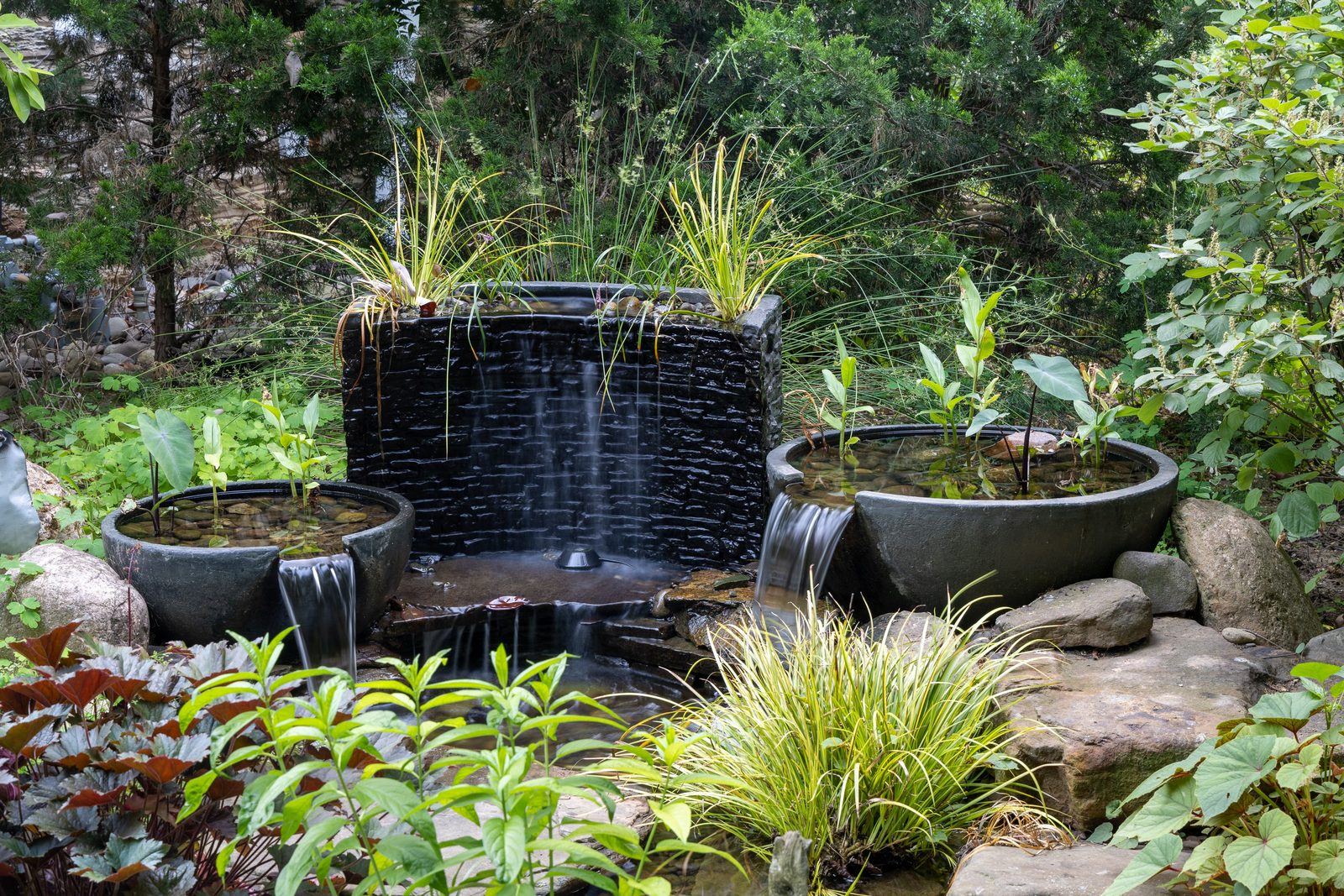 Slate wall fountain with twin spillway bowls and ornamental grasses by AquaReale Philadelphia