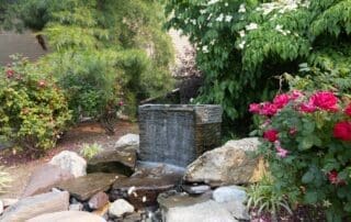 Tranquil garden waterfall surrounded by blooming flowers.