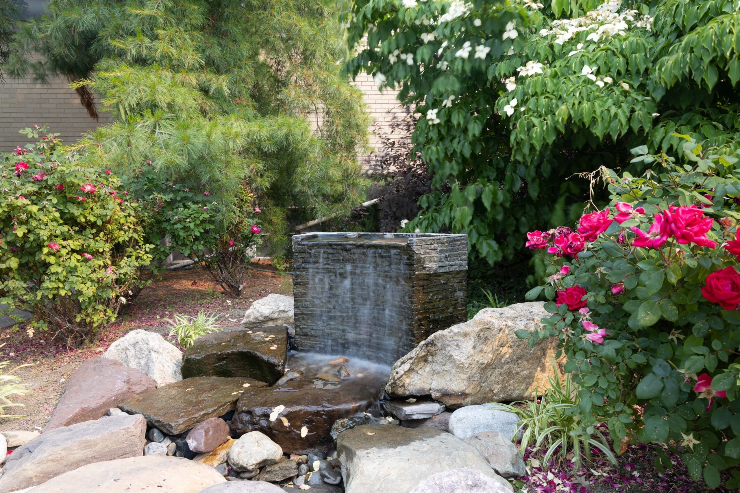 Tranquil garden waterfall surrounded by blooming flowers.