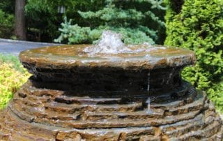 Water cascading down tiered outdoor garden fountain.