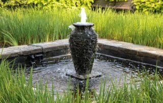 Garden water fountain surrounded by lush greenery.