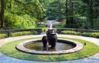 Tranquil garden with stone fountain and greenery.